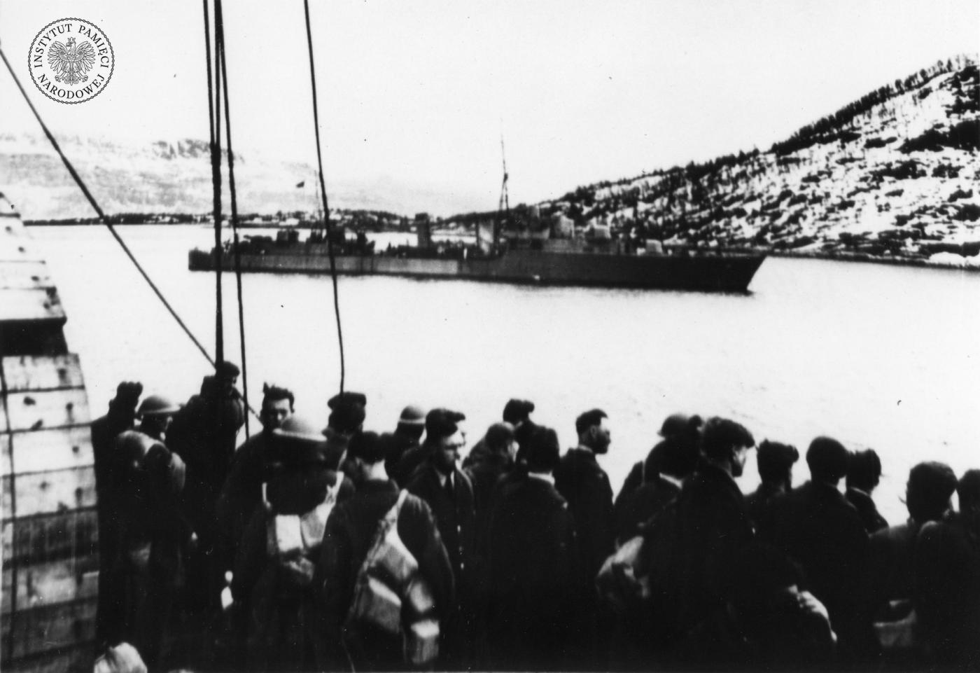 Brytyjscy żołnierze z jednostek lądowych na pokładzie transportowca po przybyciu do Norwegii  prawdopodobnie w rejonie Narwiku . W głębi fragment fiordu i stojący brytyjski duży niszczyciel typu    Tribal    fot. Archiwum IPN